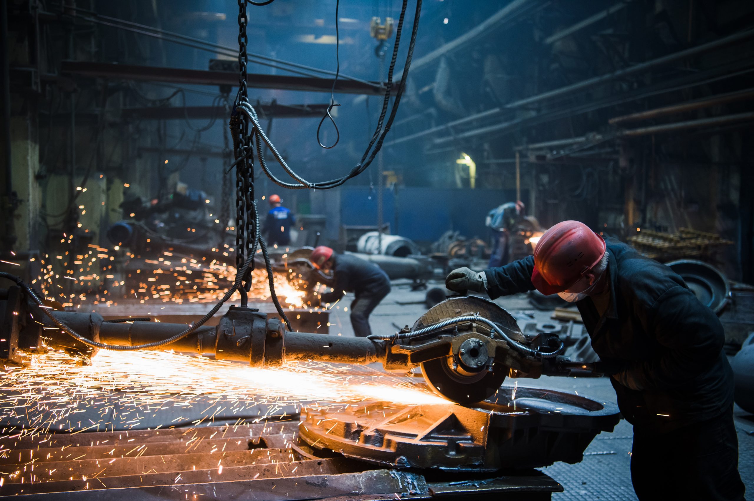 Welder used grinding stone on steel in factory with sparks.